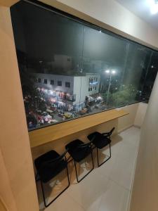 a room with a large window with three chairs in front at Suites19 in Bengaluru