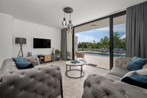 ein Wohnzimmer mit zwei Sofas und einem Fernseher in der Unterkunft Santalezi Sunset Villa 2 in Santalezi