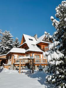 eine Blockhütte im Schnee mit Schnee in der Unterkunft Villa 11 Folk & Design in Zakopane