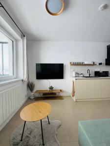 Una sala de estar con una mesa y un televisor en la pared. en Panorama View Apartment, en Veľký Slavkov