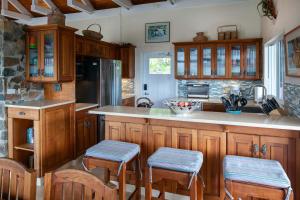 a kitchen with wooden cabinets and a counter with stools at Maria Breeze Villa - Stunning Ocean & Sunset Views Private Pool Spacious Rooms in Contant