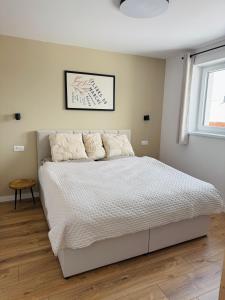 Un dormitorio con una cama con sábanas blancas y una ventana. en Panorama View Apartment, en Veľký Slavkov