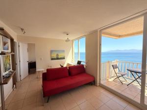 ein Wohnzimmer mit einem roten Sofa und einem Balkon in der Unterkunft Bahia Pelicanos Apartment in Horcon Puchuncavi in Puchuncaví