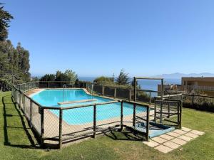 ein Schwimmbad mit einem Zaun um ihn herum in der Unterkunft Bahia Pelicanos Apartment in Horcon Puchuncavi in Puchuncaví + 13 Fotos
