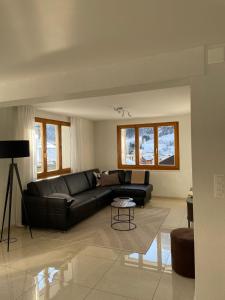 a living room with a black leather couch at Apartments Soldanella in Leukerbad +30 photos