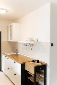 eine Küche mit weißen Schränken und einer Holzarbeitsplatte in der Unterkunft Spacious 1BR Designer Apartment in Sloboština in Zagreb + 44 Fotos