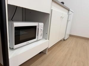 un microondas sentado en un estante en una cocina en Le cocon douillet, en Oyonnax