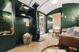 a living room with green walls and a fireplace at Nestledstays - The Hide in Walberton