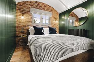 a bedroom with green walls and a bed with a mirror at Nestledstays - The Hide in Walberton