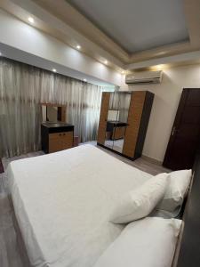 une chambre avec un grand lit blanc et un bureau dans l'établissement شيراتون للخدمات الفندقيه الفاخره, au Caire