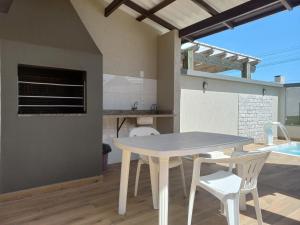 einen weißen Tisch und Stühle in einer Küche mit einem Tisch in der Unterkunft Casa Com Piscina Pertinho Do Mar Em Capão Da Canoa in Capão da Canoa
