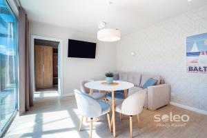 a living room with a table and chairs and a couch at SOLEO Family Resort - domki 3 min od Morza - 3 Baseny, 3 Jacuzzi, Sauna, ANIMACJE, Małpi Gaj, 3 Sale Zabaw, 4 Place Zabaw, 2 Restauracje in Rewal +39 photos