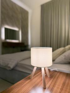 马斯喀特Al Azaiba apartment的卧室里，木桌上摆着一盏白色台灯。