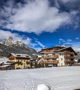 Cesa Bernard - Apartment Cima 12 e new Apartment Fraine في بوتسا دي فاسّا: مبنى في الثلج عليه اثار اقدام في الثلج