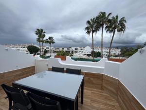 einen Balkon mit einem Tisch, Stühlen und Palmen in der Unterkunft Parque Don José 189 in Arona