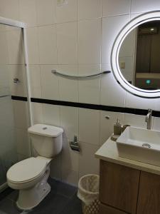 a bathroom with a toilet and a sink and a mirror at Torre Imperial Apartamento in Maracay +5 photos