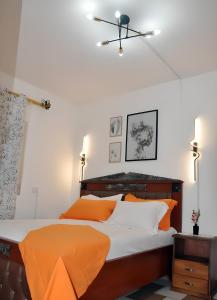 a bedroom with a bed with orange and white pillows at Charmant Douillet à Etoudi in Yaoundé