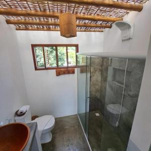 a bathroom with a toilet and a glass shower at Pousada Vila Cacau in Serra Grande