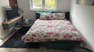 ein Schlafzimmer mit einem Bett mit einer rosa Bettdecke und einem Tisch in der Unterkunft Apartman Nina in Foča