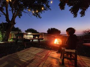 a little girl sitting on a bench next to a fire at חאן בכרמל in Qiryat H̱aroshet