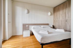 a bedroom with a bed with white sheets and wooden floors at GiaxTower Gym Spa & Pool Bright Space in Milan +27 photos