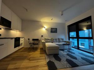 Una sala de estar con un sofá blanco y una cocina. en Apartamenty Forestlive, en Międzychód 6 fotos más