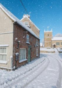 un bâtiment en briques avec une porte verte dans la neige dans l'établissement The Old Shop at Savile House - Sherwood Forest, à Ollerton