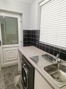 a kitchen with a sink and a washing machine at King Edward 3 bed house ideal for contractors in Darlaston