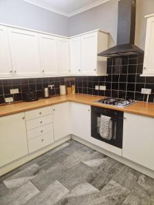 a kitchen with white cabinets and a stove top oven at King Edward 3 bed house ideal for contractors in Darlaston