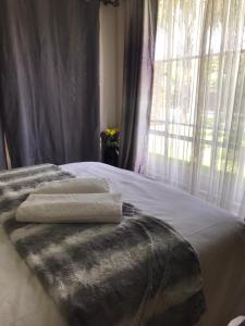 a bed with two towels on it with a window at TANS Garden Cottage in Centurion