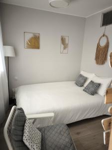 un lit blanc dans une chambre avec une chaise dans l'établissement Golf & Playa a 1 min, à Grao de Castellón