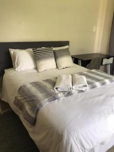 a white bed with three pillows on top of it at TANS Garden Cottage in Centurion