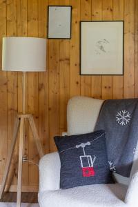 a room with a chair with a pillow and a lamp at Le Petit Mayen in Châtel-Saint-Denis
