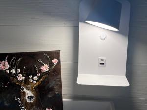 Una luz en una pared con una pintura de un ciervo. en Vara Hemma, en Smedamåla