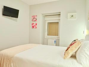 a white bedroom with a bed and a window at Casa CAMPELO- Playas de Pinténs - CANGAS-HIO- Ría de Aldán in Cangas de Morrazo