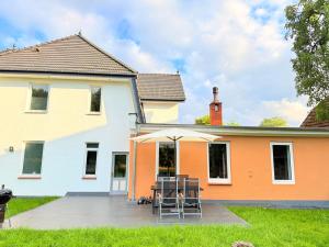 a house with a patio with chairs and an umbrella at Whisperwood Apartment in Colnrade