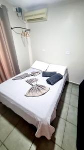 a bedroom with a bed with white sheets and blue towels at Edícula Roma - Casa de hóspedes in Campo Mourão