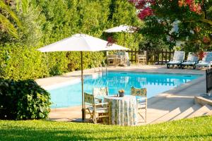 un tavolo con ombrellone e sedie accanto a una piscina di Aldeia da Graça a Guimarães