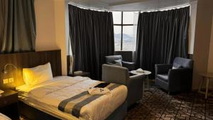 une chambre d'hôtel avec un lit et deux chaises dans l'établissement فندق الأولين حياة - مكه, à Ash Shishah 15 autres photos