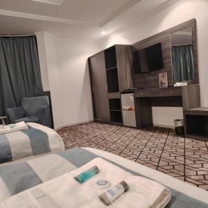 une chambre d'hôtel avec deux lits et un bureau dans l'établissement فندق الأولين حياة - مكه, à Ash Shishah