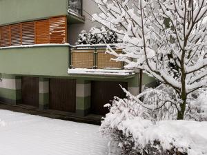 Un edificio cubierto de nieve con un balcón y un árbol. en Home4You, en Cracovia