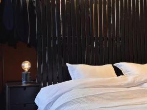 ヘルシンキにあるDesign home with sauna and spa in central Helsinkiのベッド(黒いヘッドボード付)、テーブルの上のランプ