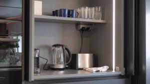 ヘルシンキにあるDesign home with sauna and spa in central Helsinkiの棚にティーケトルとカップが置かれたキッチンカウンター