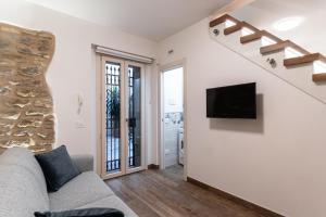 Una sala de estar con un sofá y un televisor en una pared. en L'Angolo della Torre, en Bevagna
