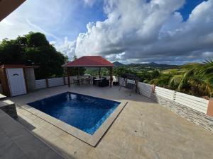 a swimming pool on a patio with a gazebo at Bas de villa Meilya in Le Marin