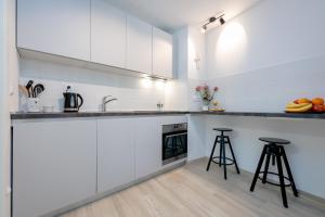 a kitchen with white cabinets and two bar stools at Studio Apartment "Dida" with Free Private Parking in Solin