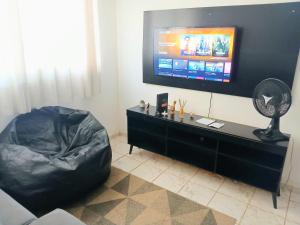 a living room with a flat screen tv and a couch at Apto 02 quartos com ar ao lado do Parque das Águas in Cuiabá
