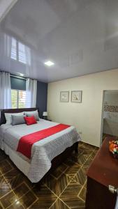 um quarto com uma cama grande e uma almofada vermelha em Springhouse jarabacoa em Jarabacoa