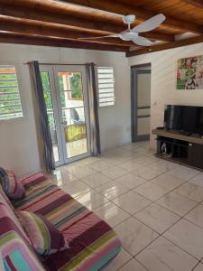 a living room with a couch and a flat screen tv at Villa Nanou , Haut de villa calme et petite vue sur Mer in Bouillante