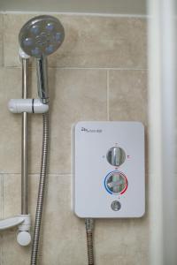 une pomme de douche et un serpentin de douche dans une salle de bains dans l'établissement Modern Cozy Flat 6 mins to City Parking & WiFi, à Killingbeck